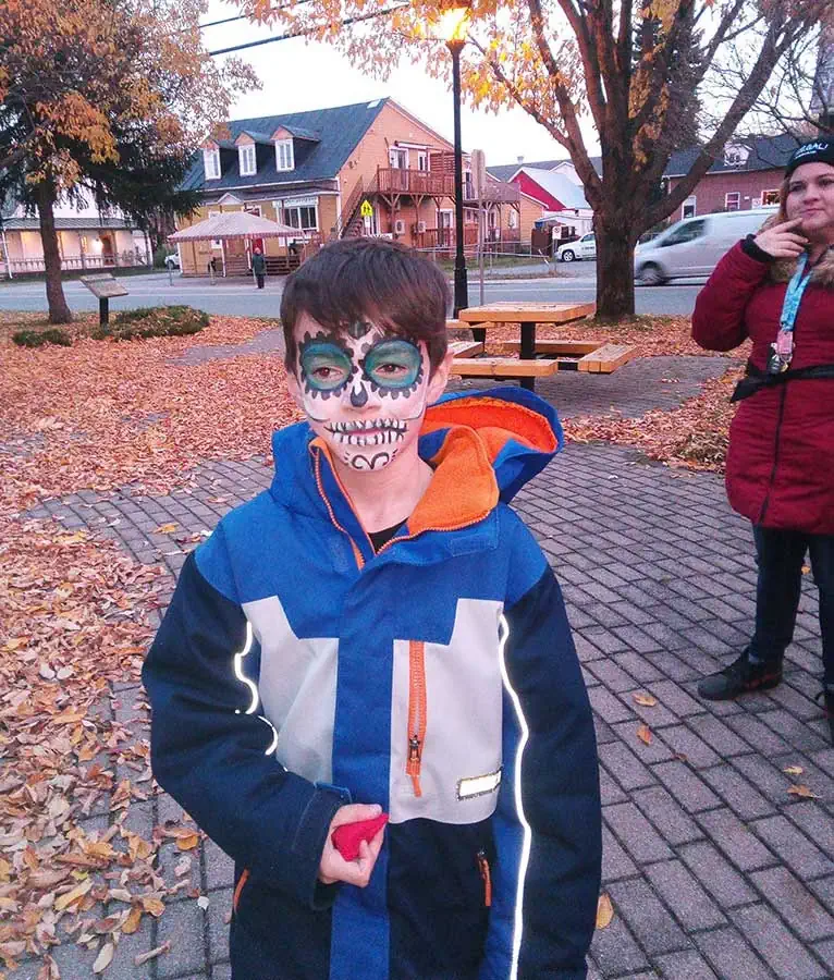 Un enfant maquillé en squelette coloré regarde la caméra