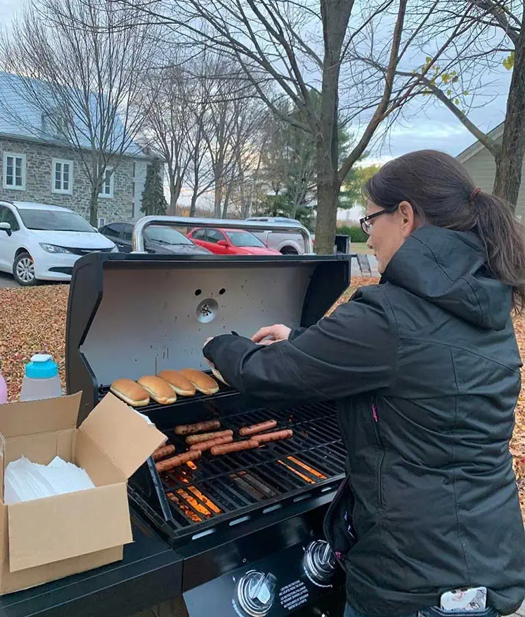 Une femme fait griller des hot dogs dans un BBQ à l'occasion de la Nuit des sans-abris à Bécancour.