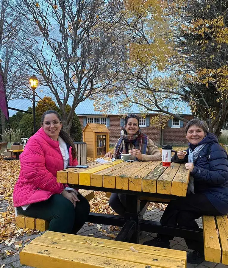 Trois femmes assises à une table à piqueniquer sourient à la caméra