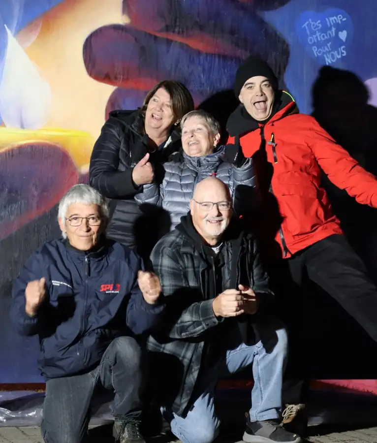 Des gens se tiennent en souriant devant la murale
