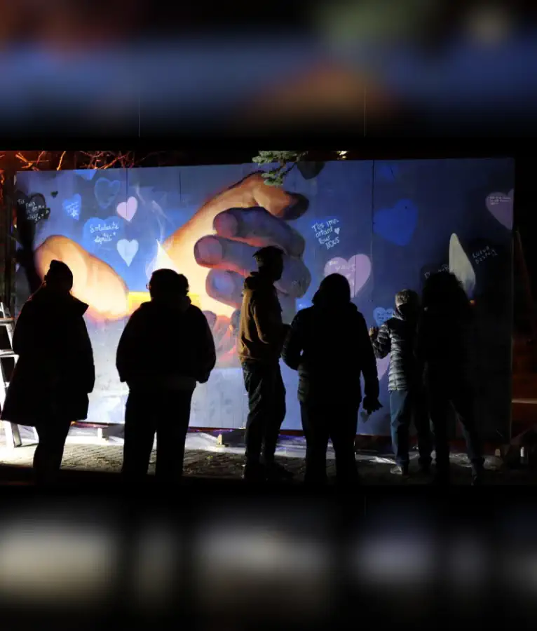 Ombres de personnes se tenant devant la murale de sensibilisation à l'itinérance